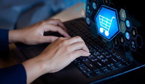 double-exposure-shopping-cart-businesswoman-using-laptop